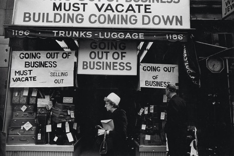 7. Simpson Kalisher, Untitled, ​1962. Two pedestrians pass a storefront with various &quot;Going out of business&quot; signs and stacks of suitcases in the shop window.