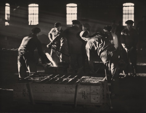Ralph Bartholomew, Steinway Piano Factory, ​c. 1935. Dark factory scene with light streaming in from the left. Workers perform various tasks including pouring molten metal.