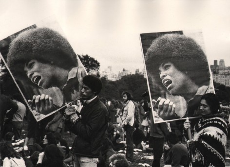 02. Beuford Smith, Angela Davis demonstration, Central Park, NY, ​1972. A crowd of protesters; two hold large signs with photos of Angela Davis.