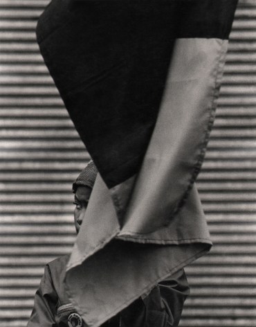 07. Beuford Smith, Woman &amp; Flag, Harlem, ​1969. A small portion of a woman's face is seen from behind a large flag that hands above and in front of her.
