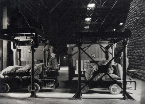 Harold Haliday Costain, Edgewater, NJ Sugar Refinery, ​1935. Two men load sugar sacks onto carts.