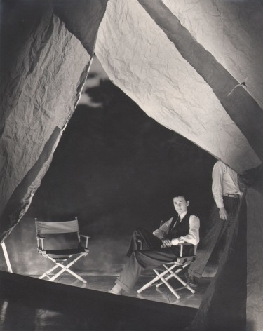 George Platt Lynes, Alfonso Ossorio, n.d. Subject is seated on the right of two directors' chairs beneath backlit fabric hanging from above.