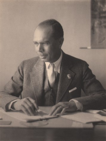 Doris Ulmann, James Weldon Johnson, ​c. 1925. Subject is seated at a desk, writing and looking to the left.