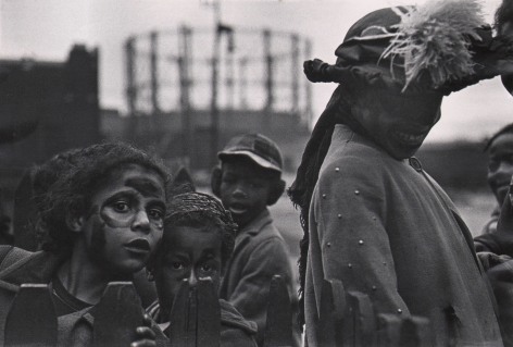 Marvin E. Newman, Chicago, ​1950. Children wearing face paint and a woman in a large feathered hat look to the camera in curiosity.