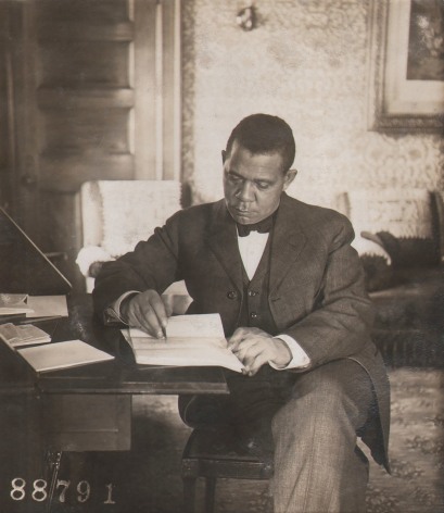 Underwood &amp; Underwood, Booker T. Washington, ​1906. Subject is seated at a desk, writing and looking down.