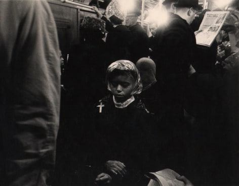 04. Beuford Smith, Palm Sunday, ​1968. A woman seated on a crowded subway, hands crossed in her lap and eyes closed.
