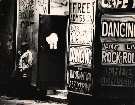 10. LeRoy Henderson, Cafe Wha! Greenwich Village, N.Y. (MacDougal Street), ​c. 1965. Man leas against building covered in signs such as &quot;Free admission,&quot; Live Rock n' Roll,&quot; and &quot;Dancing&quot;