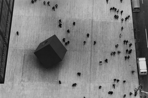 01. Larry Herman, A Noguchi sculpture in the Wall Street area of New York City. Photographed from thirty floors above street level, c. 1967. Birds-eye view of small human figures milling about a large dark cube.