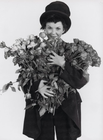 Richard Avedon, Judy Garland, ​1951. A woman in a suit and top hat holds a large bouquet of flowers.