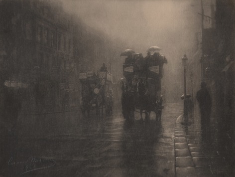 03. L&eacute;onard Misonne, Rue royale, 1936. Two horse-drawn carriages carrying figures with umbrellas on a wet street. Sepia-toned print.