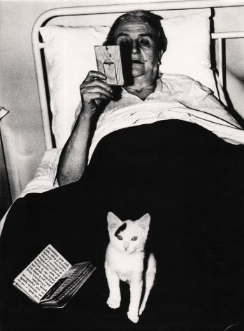 07. Mario Giacomelli, Verr&agrave; la morte e avr&agrave; i tuoi occhi, 1966&ndash;1968. High contrast image. A woman in bed with a book and kitten in her lap, looking at a small frame in her right hand..