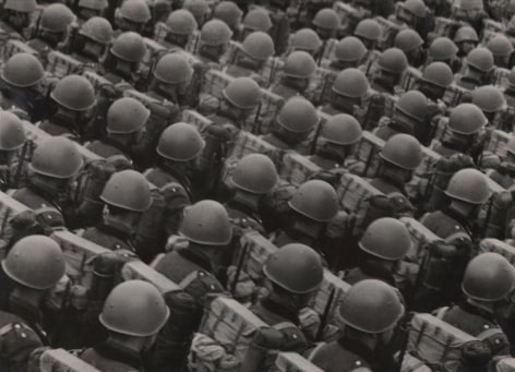 Italo Bertoglio, Le case di fronte, c. 1937. Diagonally composed rows of soldiers in helmets photographed from behind.