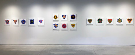 Sixteen works on paper by Jack Youngerman under plexi box frames installed on white walls