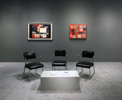 Two paintings by Alice Trumbull Mason installed on dark grey walls with three chairs and a table in the foreground