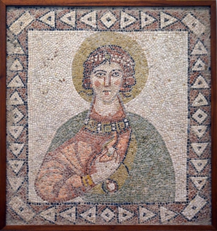 A mosaic depicting the haloed virgin mary holding a pearl and wearing a crown and comprised of earth-toned marble, volcanic stone and limestone