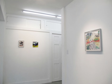 A photograph of 3 artworks: 1 on the close wall at right, 2 on a wall at left