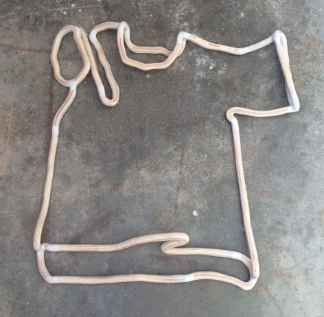 An outline of a t-shirt made out of thin plywood, made to resemble a single line