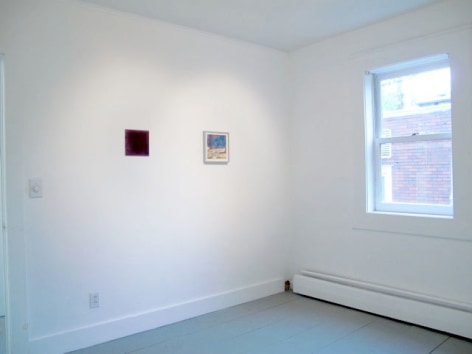A photograph of 2 artworks on a wall at left, a window is at right