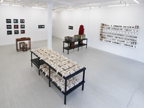 An installation view of Dayanita Singh's exhibition, which includes a table holding wrapped &quot;Pothi Box&quot; book-objects, &quot;Museum of Gestures,&quot; a custom desk with 2 chairs, two diptychs (&quot;Mona and Louise,&quot; &quot;Mona and Myself&quot;) hung on the back wall, &quot;File Room Book case&quot; on a black shelf, and &quot;Sent a Letter&quot; installed on 7 shelves.