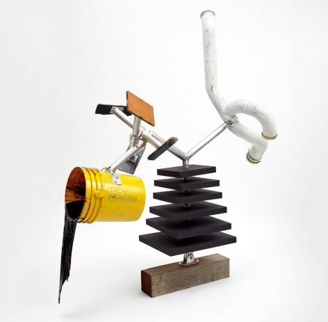 A mixed media sculpture of a yellow bucket, resin, a white tube, and layered wooden slabs