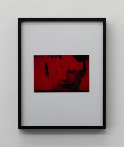 An image in red and black of a boy's face, framed in black