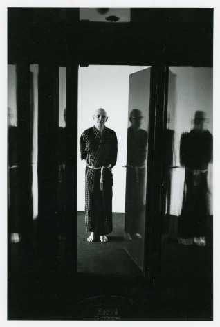 A black and white photograph of Michel Foucault in a doorway, dressed in a kimono