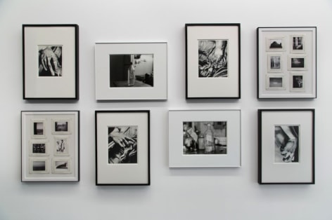 A straight-on photograph of 8 black and white images, framed, in a salon hang.