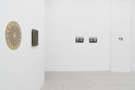 An installation view of 2 mandala works at left (cardboard, wood board) with 2 more works on the far wall. The far wall has 2 photographs, and one small drawing.
