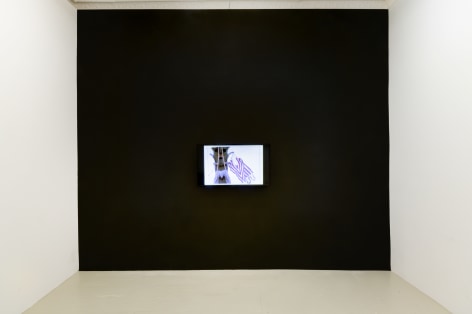 a black wall onto which a flat panel monitor is hanging that is displaying an animated video
