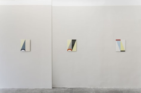 Three enamel paintings hung on a gray wall