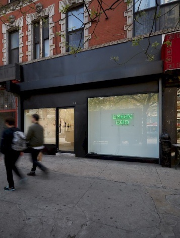 A photograph of the exterior of the gallery from the sidewalk, where the neon sign &quot;Green God&quot; is visible.
