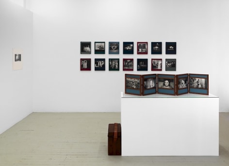 A photograph of the front quadrant of the gallery: Dayanita Singh's unfurled book-object on a pedestal is in the foreground; the background has 2 rows of Dayanita's &quot;Museum of chance&quot; book-objects; at left on the temporary wall is a black and white photograph by Guibert.