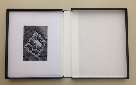 A photograph of an open binder with a single black and white photograph on top.