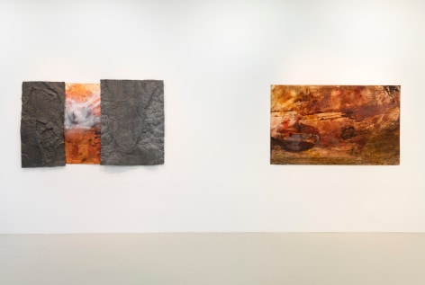 two paintings hanging on the wall where both works have orange brown and white colors in gestures that look like tumultuous sea scapes and the painting on the left has textured metal components attached to the surface