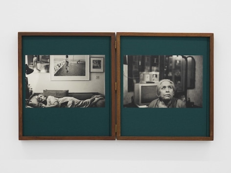 A set of two books within teak wood enclosures. Their covers have teal linen, and 2 black and white photographs adhered to the cover. There are hinges in the middle of the object so it could fold in half. The image at left is Mona laying on a couch with photographs and artworks on the wall. The right image is Mona looking up, with a television behind her and a mirror