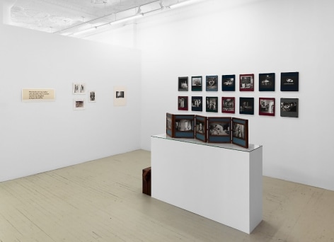 A photograph of the front quadrant of the gallery: there is a pedestal with an unfurled photography book-object by Dayanita Singh and 2 row of Dayanita Singh's &quot;Museum of chance&quot; on the right wall; at the left temporary wall is a series of 5 artworks in varied sizes, hung salon-style.