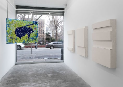 A photograph of the gallery looking out, with 3 works on the right wall and one hanging painting