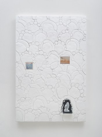 A photograph of a predominantly white surface that has 3 collage elements upon it that depict artworks (2 landscapes, 1 set of praying hands). There are circles carved into the surface that appear like soap suds in cartoon-form.