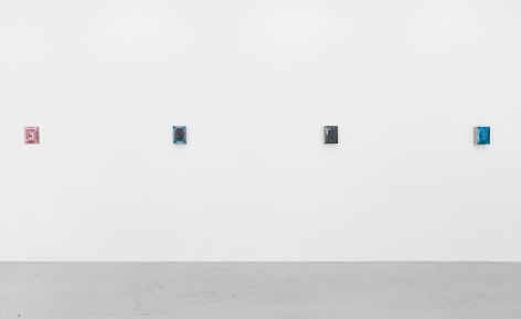 A single wall straight on with four small abstract paintings, who's detailed are indiscernible.