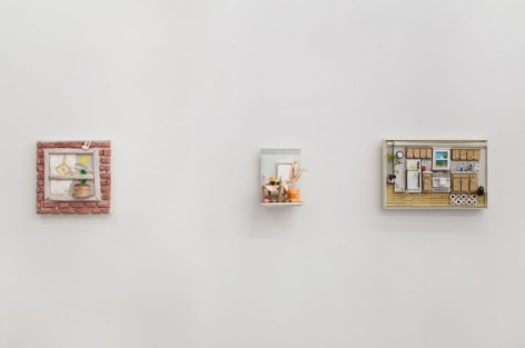 A photograph of 3 friezes depicting domestic city scenes, sculptural, on the wall.