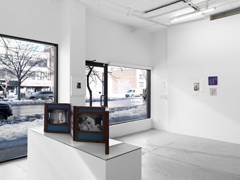 A photograph of the front quadrant of the gallery with the gallery's windows. Dayanita Singh's unfurled book-object on a pedestal is in the foreground; in the background are 2 drawings by Bracha Ettinger, and one photograph to the left of them.
