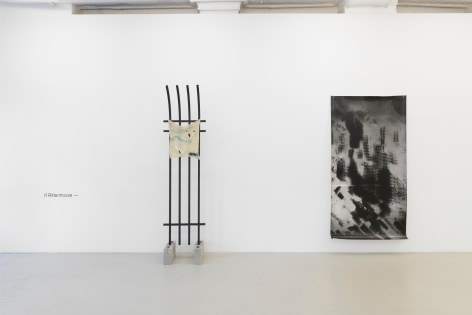 installation view showing the title of the show, the fence sculpture and a large black and white photograph that is tacked to the wall and that depicts an abstraction of draped netting commonly seen on construction sites