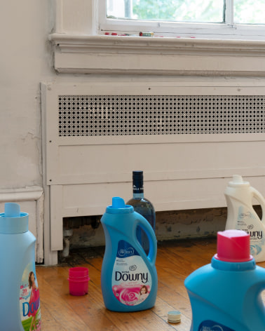 A photograph close-up of open detergent bottles and lipstick, M&amp;Ms on the windowsill