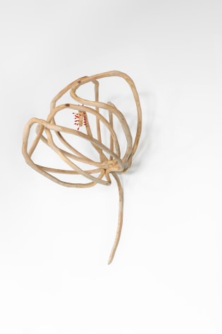 A sculpture of a flower silhouette hung on a wall, made of wood spindrels