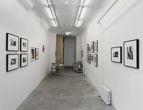 A view of the gallery from the front, with images installed salon-style throughout.