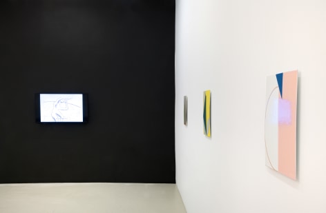 a black wall with a monitor hanging on it and three geometric abstract paintings in different colors viewed from the side