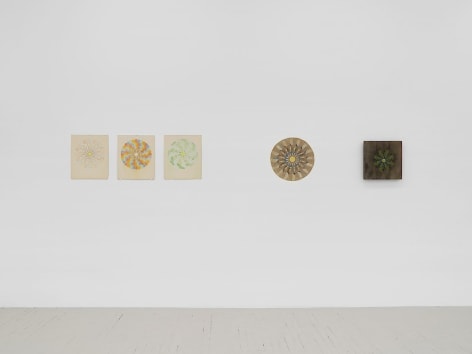 Left to right: an installation of three mandala drawings (colored pencil on paper), one mandala depicted on cardboard, and a mandala on a piece of wood.