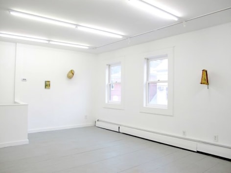 A photograph of 3 artworks hung on 2 walls, separated by 2 windows