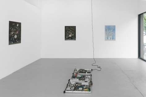 A photographs of 3 paintings of a still life of flowers with a circuit board sculpture on the ground.
