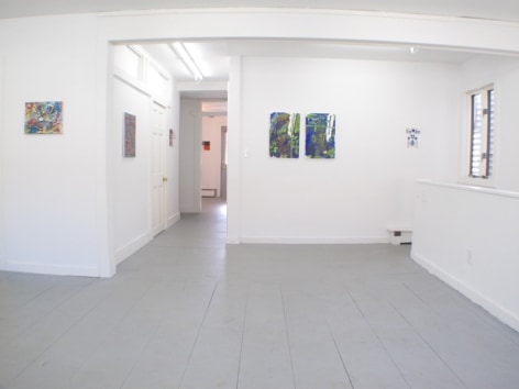 A photograph of the gallery with 2 works in the hallway, one work at left and 3 at right in the main room, and one work visible at the end of the hallway in the background